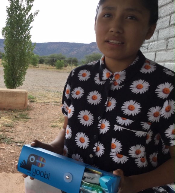 A girl from the Apache tribe in Whiteriver, Arizona is blessed with some new school supplies, including the Yoobi pencil box that she's holding. 